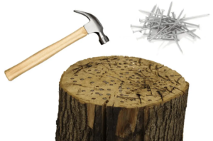 Spijkerslaan: een hamer, losse spijkers en een boomstam vol spijkers